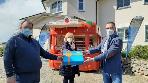 WEMACOM Geschäftsführer Volker Buck (rechts) übergibt im Beisein von Landrätin Kerstin Weiss symbolisch den Router an Betriebsleiter Jan van Leeuwen auf dem Erdbeerhof Glantz.