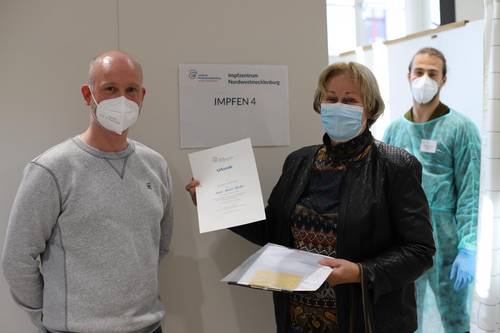 Nach ihrer Auffrischungsimpfung durch Impfarzt Roman Stiefel überreichte Impfmanager Tom Brose zur Erinnerung an die 100.000. Impfung im Landkreis eine Urkunde Karin Harder (81).
