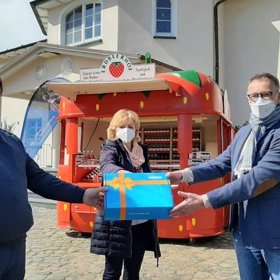 WEMACOM Geschäftsführer Volker Buck (rechts) übergibt im Beisein von Landrätin Kerstin Weiss symbolisch den Router an Betriebsleiter Jan van Leeuwen auf dem Erdbeerhof Glantz.