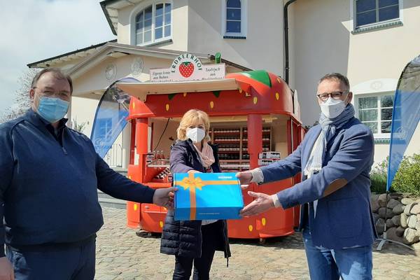 WEMACOM Geschäftsführer Volker Buck (rechts) übergibt im Beisein von Landrätin Kerstin Weiss symbolisch den Router an Betriebsleiter Jan van Leeuwen auf dem Erdbeerhof Glantz.