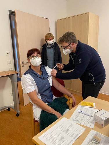 Landrätin Kerstin Weiss sieht zu, wie DRK-Mitarbeiterin Bärbel Ziehn-Teude (59) in der DRK-Wohnanlage in Schönberg ihre Impfung von Dr. Carsten Sommerfeldt bekommt.