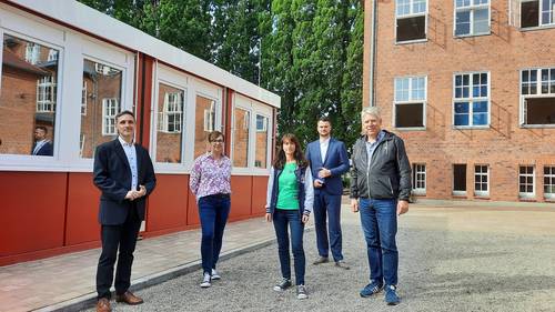 (von links) Der Bürgermeister von Schönberg Stephan Korn, Elternratsvorsitzende Sandra Brick, stv. Schulleiterin Susanne Pelka, Landrat Tino Schomann und Kreistagspräsident Thomas Grote zwischen Altbau und der neuen Containerlösung.