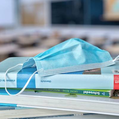 Ein medizinischer Mundschutz liegt auf Büchern