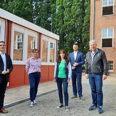 (von links) Der Bürgermeister von Schönberg Stephan Korn, Elternratsvorsitzende Sandra Brick, stv. Schulleiterin Susanne Pelka, Landrat Tino Schomann und Kreistagspräsident Thomas Grote zwischen Altbau und der neuen Containerlösung. © LK NWM (von links) Der Bürgermeister von Schönberg Stephan Korn, Elternratsvorsitzende Sandra Brick, stv. Schulleiterin Susanne Pelka, Landrat Tino Schomann und Kreistagspräsident Thomas Grote zwischen Altbau und der neuen Containerlösung.