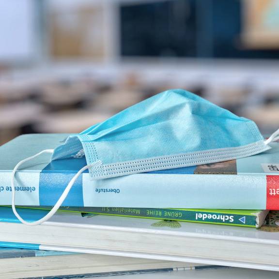Ein medizinischer Mundschutz liegt auf Büchern