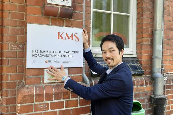 KMS-Direktor Hidehisa Edane zeigt, wo das neue Logo an der Kreismusikschule in Wismar hängen wird.
